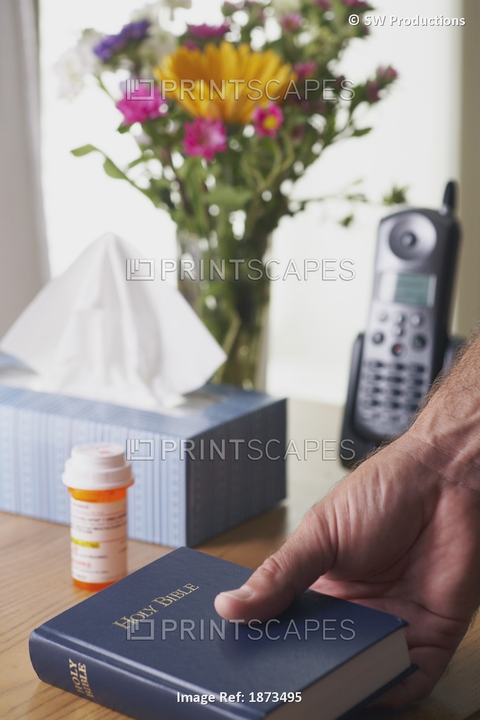 A Hand Picking Up A Bible Beside A Bottle Of Medication