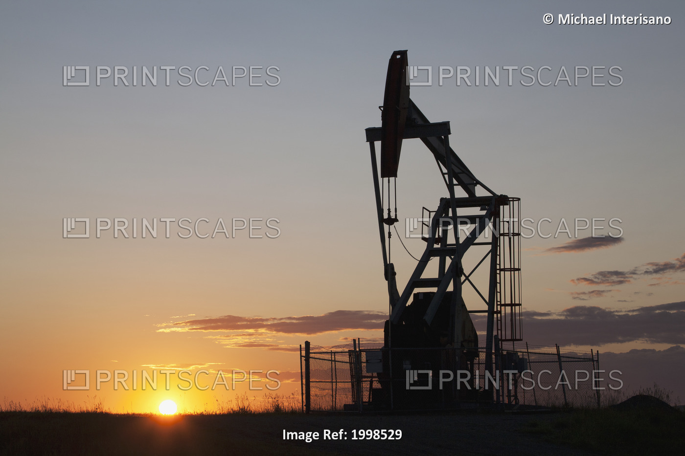 Silhouette Of Pump Jack With The Orange Glow Of The Sun Rising On The Horizon; ...