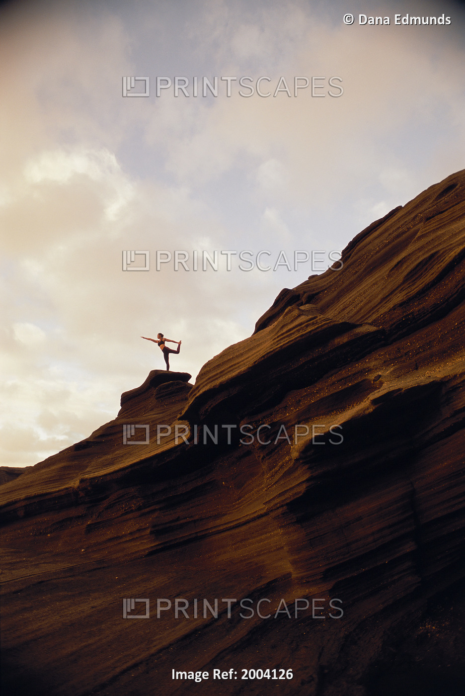 Woman Yoga At Sunrise On Rock Coastline Cliff, Side View Upward Against Clouds