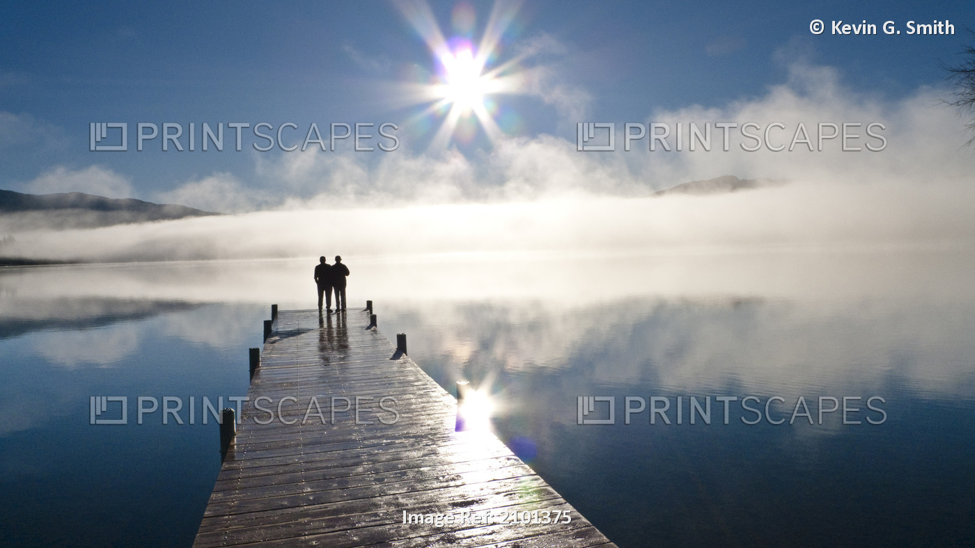 Couple Standing On A Dock And Silhouetted Against The Fog Lifting From Lake ...