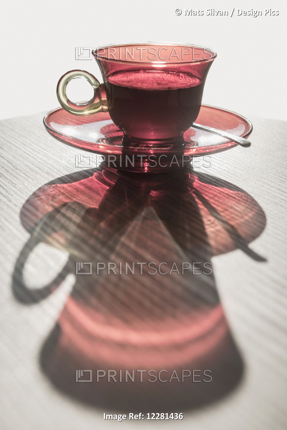 A Red Glass Cup A Saucer With A Beverage Reflected On A White Surface; Locarno, ...