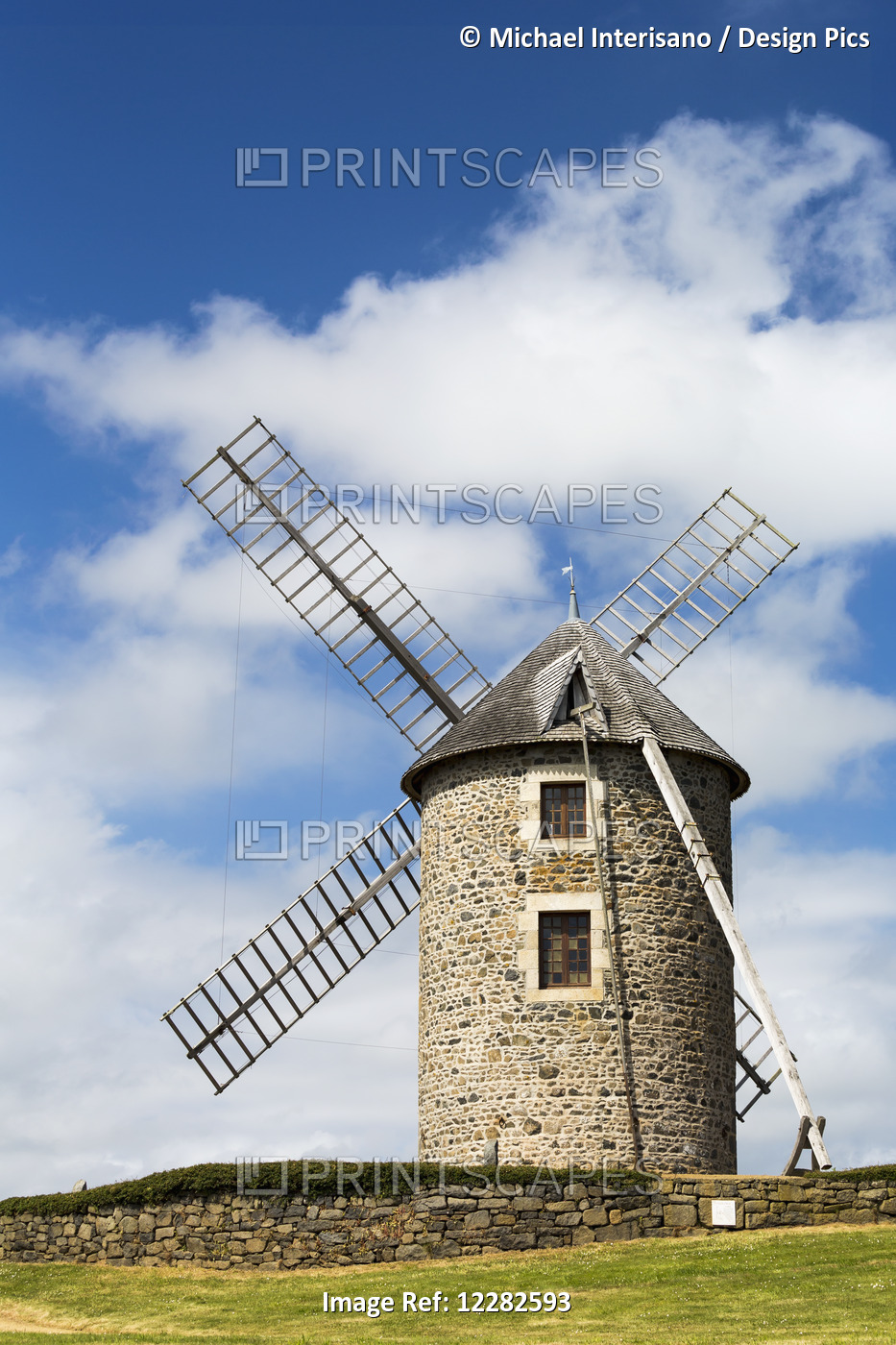 An Old Stone Windmill On A Hillside With Wooden Blades, Surrounded By A Stone ...