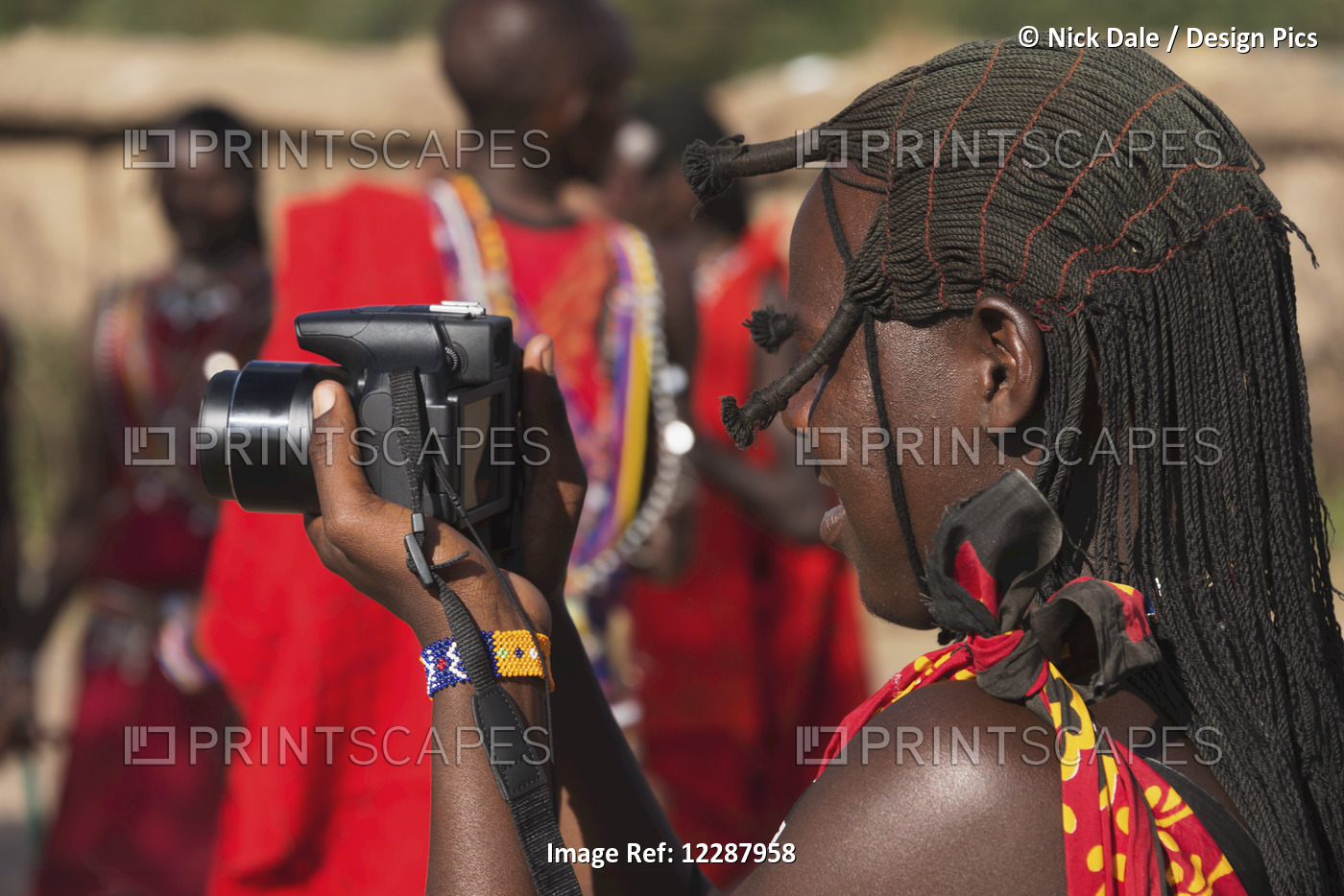 A Masai Woman In Traditional Dress Is Taking Pictures Of Other Masai While ...