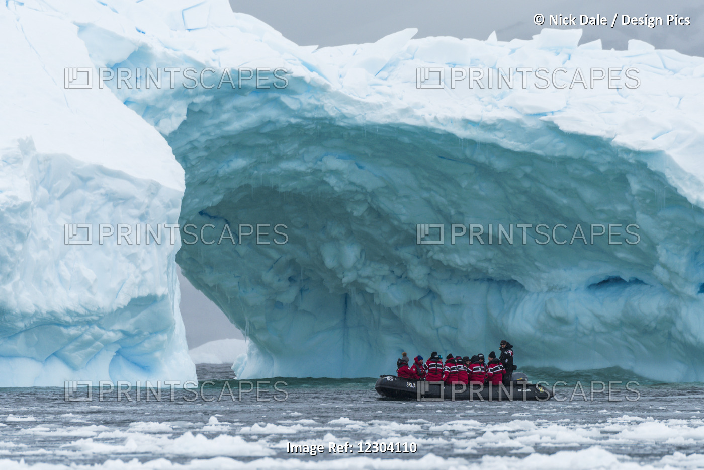 Black Inflatable Boat Going Towards Iceberg Arch; Antarctica