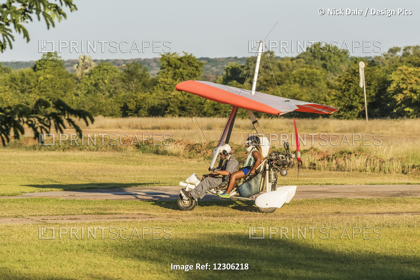 Pilot And Passenger Landing Microlight On Grass; Botswana