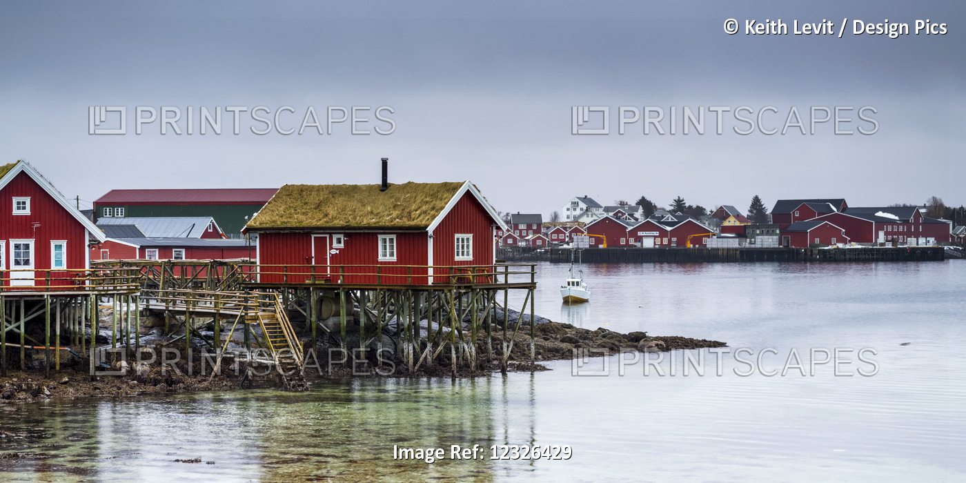 Red Buildings Along The Water's Edge Under A Cloudy Sky; Lofoten Islands, ...