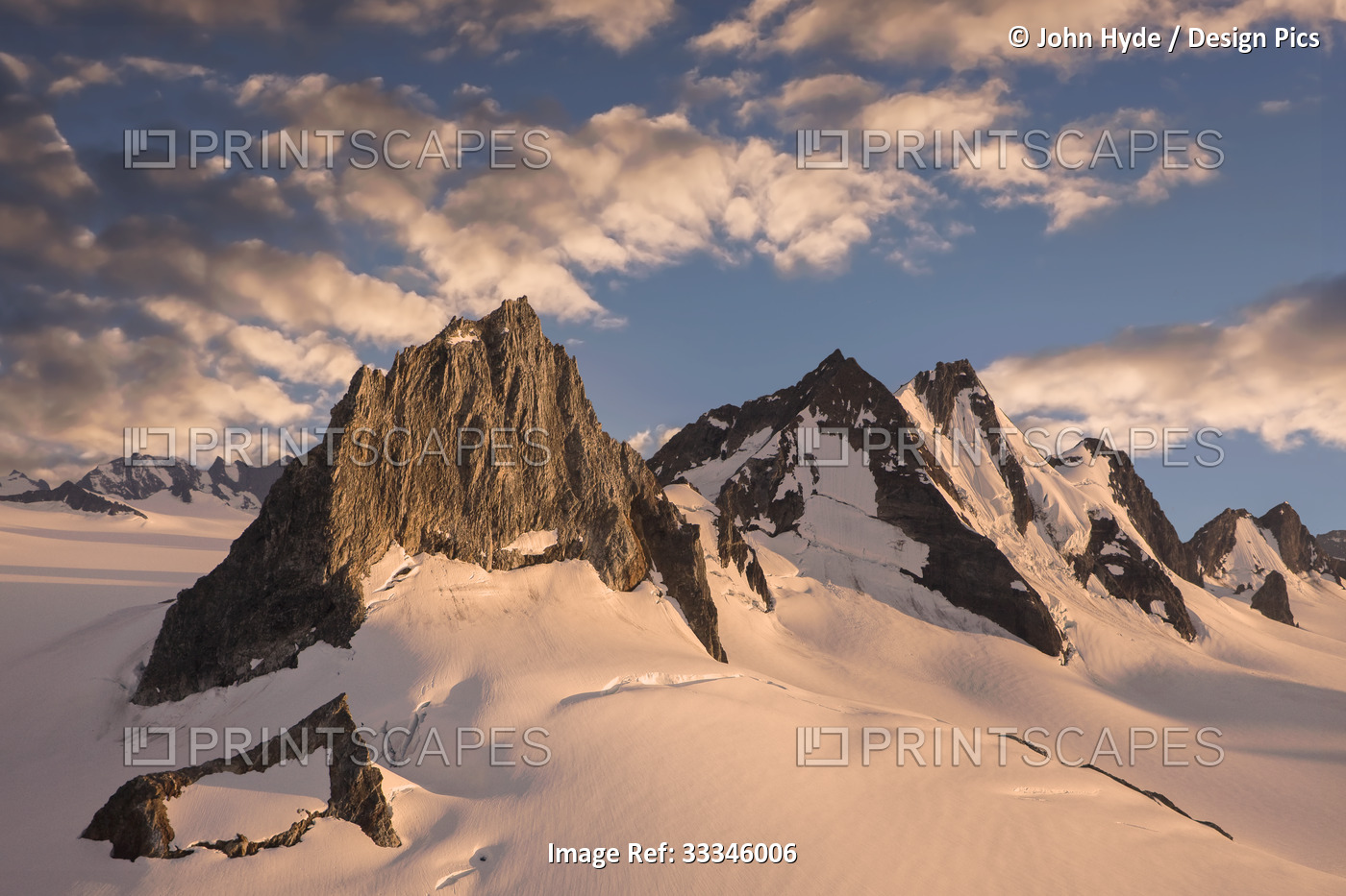 Jagged mountain peaks rise through the snowy glaciers of the Juneau Ice Field ...