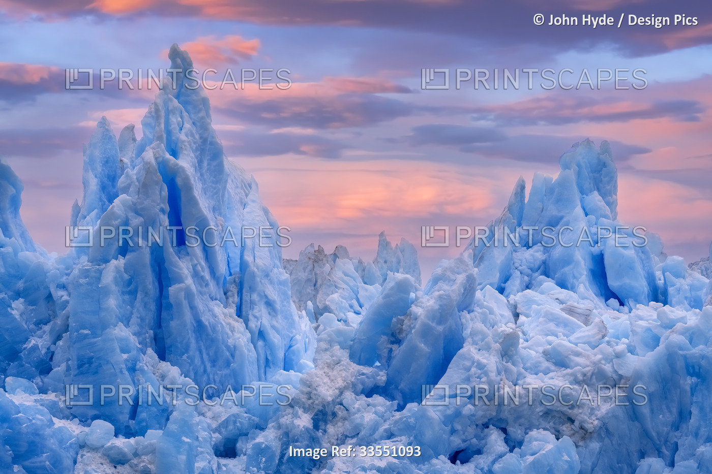 Blue ice peaks of a rugged glacial mass with a glowing pink sunset sky, South ...