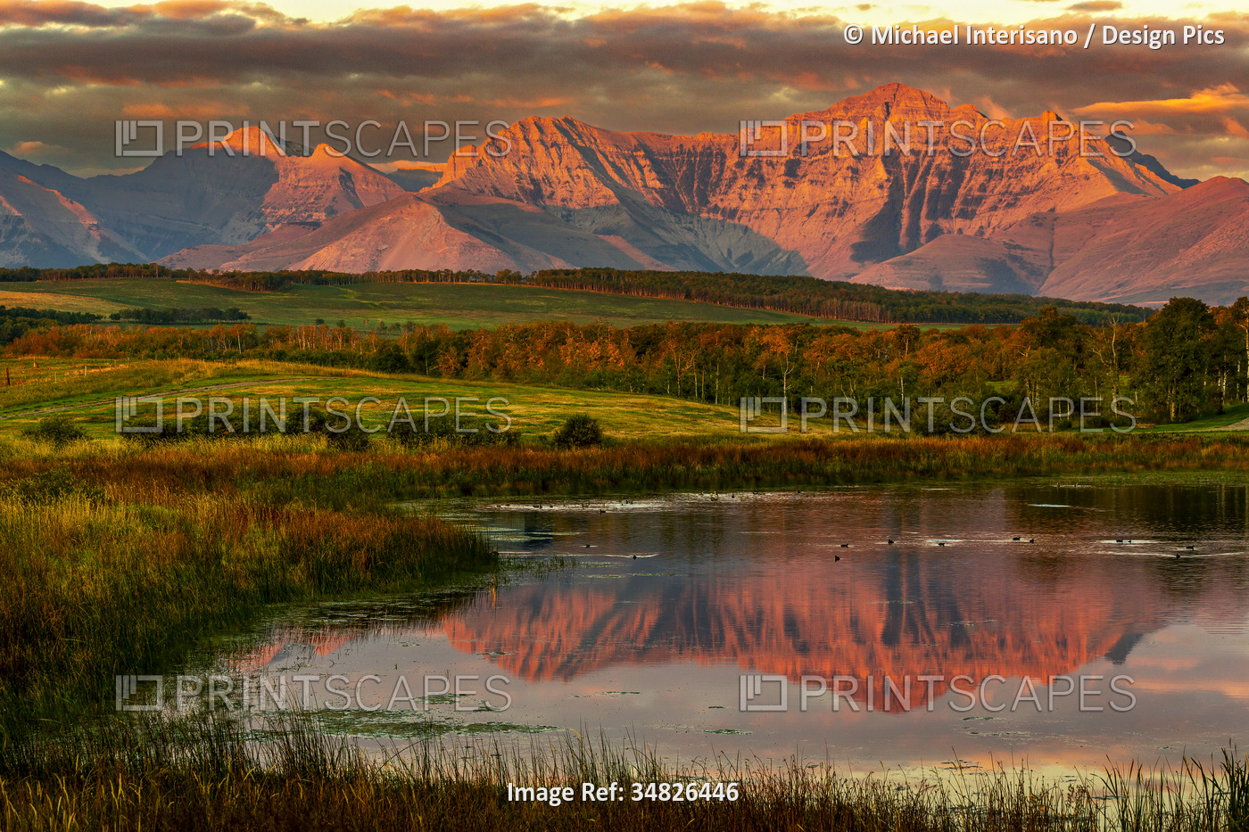 Stunning view of mountain range reflected in small lake at sunrise with warm ...